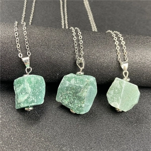Macro detail of three natural green raw stone pendants on silver necklaces in various shapes