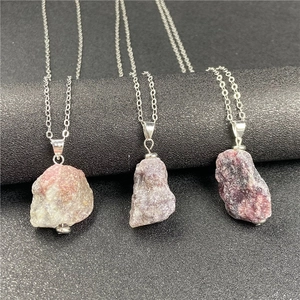 Detail of irregular natural raw amethyst and rose quartz pendants on slim silver chains