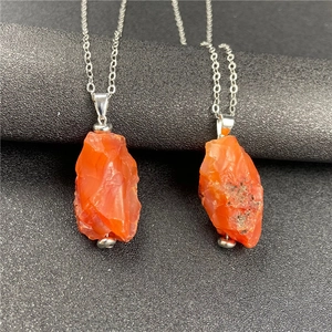 Macro detail of natural irregular orange raw gemstone pendants on silver chains