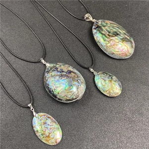 Detailed view of oval abalone shell pendants with vibrant green and blue iridescent colors