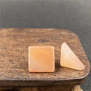 Macro di pietre di agata arancione-rosa a piramide e quadrate su base di legno