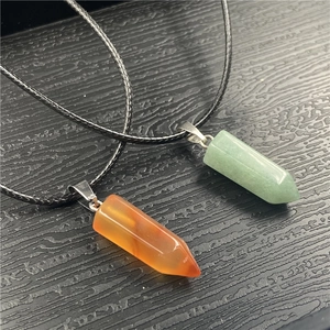 Detail view of hexagonal crystal column pendants in green and orange with black wax ropes