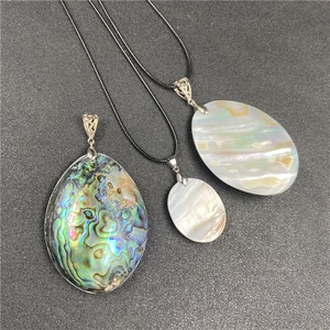 Detailed view of abalone and mother of pearl oval pendants with ornate metal bails
