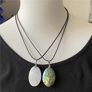 Detailed view of oval abalone and white mother of pearl pendants on black cords