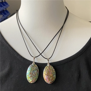 Detail of two oval abalone shell necklaces with iridescent texture on a mannequin