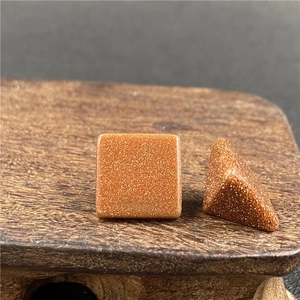 Primo piano di cabochon in goldstone quadrati e triangolari con scintille metalliche