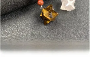 Dettaglio di una perla a stella in occhio di tigre con strisce gialle e perla rossa
