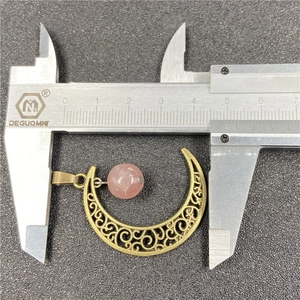 Hollow bronze moon pendant with pink gemstone bead measuring 4.4cm on a caliper
