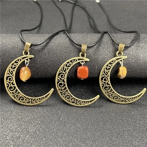 Detail view of crescent moon pendants with hollow patterns and raw stone charms