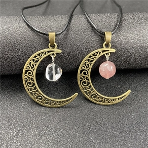 Detail of vintage bronze hollow moon pendants with raw amethyst and quartz stones