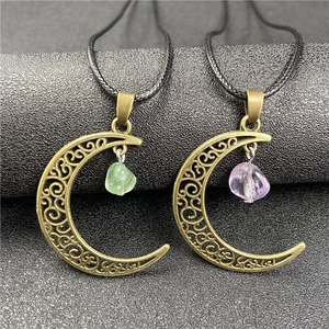 Detail of vintage bronze moon pendants with amethyst and green raw stones on black stand