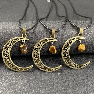 Detailed close-up of bronze moon pendants with tiger eye stones and hollow carvings