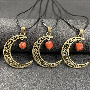 Three antique bronze crescent moon pendants with raw carnelian stones on black cords