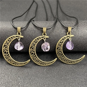 Detailed view of bronze hollow moon pendants with raw purple amethyst on black cords