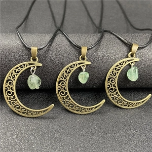 Macro detail of bronze crescent moon pendants with translucent green crystal stones