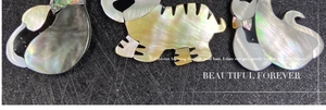 Dettaglio dei ciondoli a forma di gatto e tigre realizzati in madreperla naturale lucida