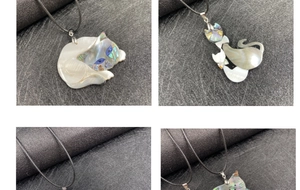 Dettaglio di ciondoli a forma di gatto fatti a mano in madreperla e conchiglia di abalone