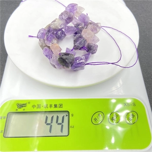 Macro shot of 44g raw amethyst crystal stone chips on a digital scale for DIY jewelry