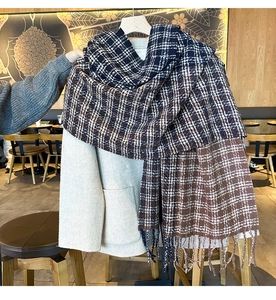 Detailed close-up of dark blue and brown plaid scarf with long fringes on beige coat