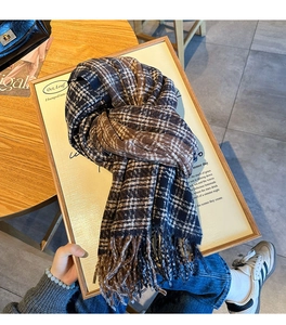 Detail of soft plaid winter scarf with fringe on rustic wooden decor with magazine