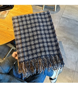 Close-up of navy blue plaid scarf texture with soft fringe details and thick knit fabric