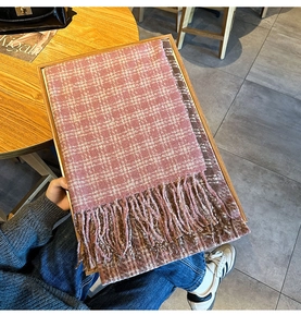 Detail of gray and brown checkered scarf with fringe on a wooden tray setting