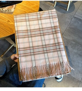 Detail of pink and beige plaid scarf with soft fringe texture on a wooden tray