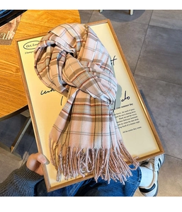 Detailed view of the soft plaid scarf with fringe on a minimalist decorative board