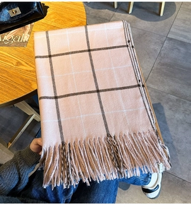 Gros plan d'une écharpe à carreaux rose avec de longues franges et une texture douce