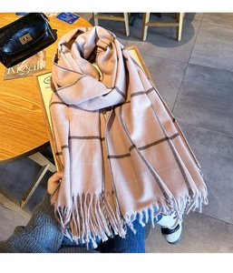 Gros plan d'une écharpe en maille à carreaux rose et gris avec franges à glands