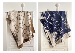 Detail of cashmere-like shawl featuring butterfly jacquard pattern in beige and navy