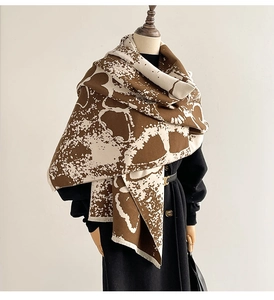 Close-up of abstract ink butterfly pattern and fringed edges on warm pashmina shawl