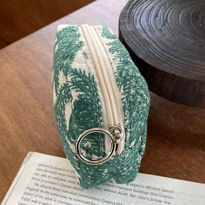 Detail of leaf embroidery on canvas pouch with a large silver ring zipper puller