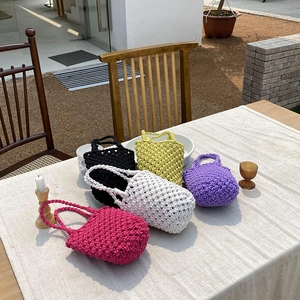 Sacs seaux tissés à la main en cinq couleurs exposés sur une table extérieure