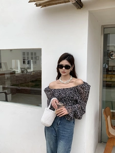 Photo extérieure d'une femme avec sac à perles blanches et haut fleuri à manches bouffantes