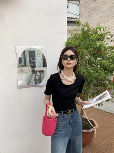 Photo style urbain d'une femme tenant un sac seau tissé à la main rose avec une tenue décontractée