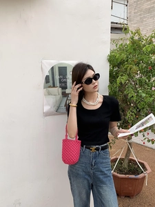 Photo en extérieur d'un sac seau tressé rose vif associé à une tenue décontractée