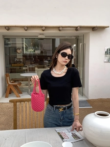 Détail du sac seau tissé rose à la main avec collier de perles et ceinture noire