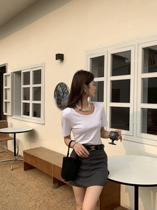 Détail d'un sac seau tissé à la main porté avec un t-shirt blanc et une mini-jupe