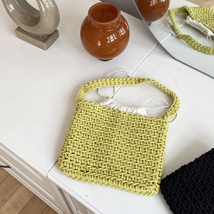 Detail of lime green hand-knitted cotton rope bag with white inner drawstring pouch