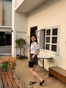 Détail d'un sac seau noir tissé à la main avec une tenue d'été décontractée chic