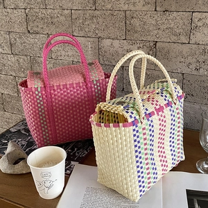 Détail de sacs cabas tissés en PVC rose et beige avec des boucles métalliques