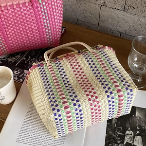 Détail du sac cabas tressé en PVC à rayures colorées sur une table en bois