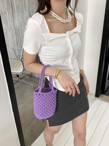 Gros plan d'un sac seau violet tricoté main avec détails de texture en maille évidée