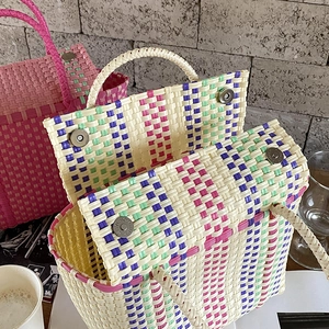 Détail de sacs cabas tissés en PVC avec rayures et fermeture à boucle en métal magnétique