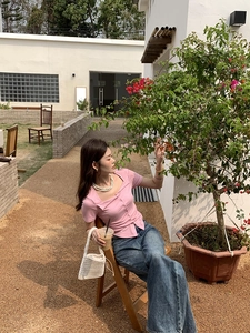 Detail of pink knit top with square neckline and button placket in outdoor garden setting