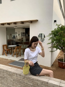 Gros plan d'un sac seau tissé à la main vert citron associé à une tenue minimaliste chic