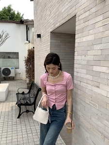 Detail of a pink short sleeve knit cardigan with a unique asymmetric square neckline