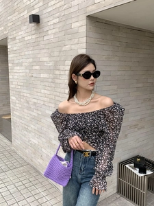 Detail view of purple hand-woven crochet bag with floral top and jeans outfit