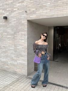 Close-up of a small purple hand-woven crochet bag with floral top and denim jeans outfit